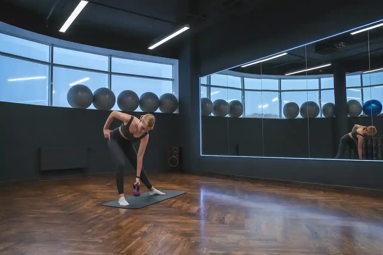 Frau trainiert mit einer Kurzhantel in einem Studio mit Spiegelwand
