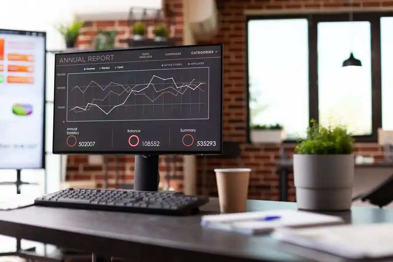 Schreibtisch mit einem Monitor, auf dem ein Auswertungs-Dashboard läuft