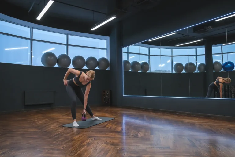 Frau trainiert mit einer Kurzhantel in einem Studio mit Spiegelwand