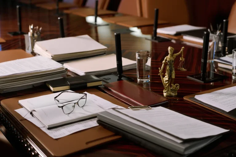 Besprechungstisch einer Kanzlei mit Akten, Brille und einer Justitia-Figur