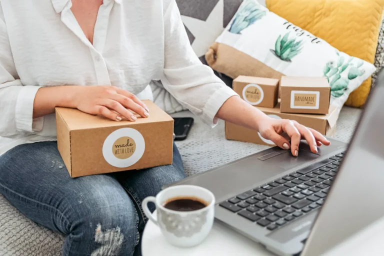 Versandpakete und ein Laptop mit geöffnetem Onlineshop